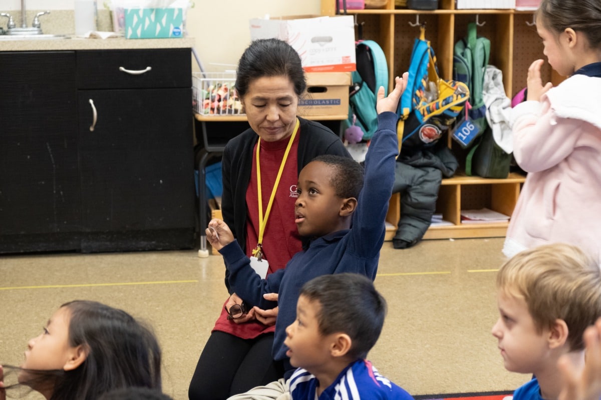 teacher sitting on floor with students